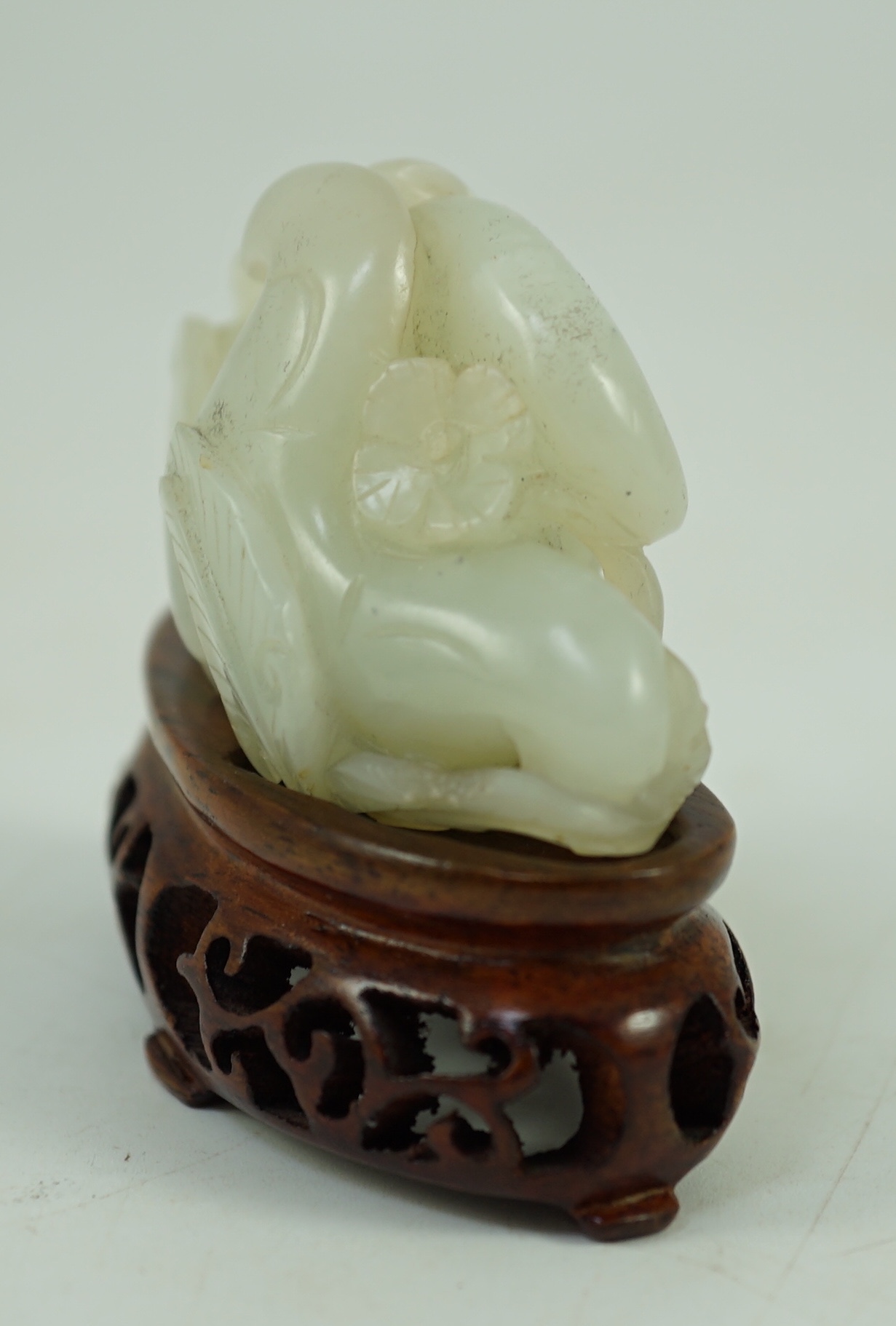 A Chinese pale celadon jade ‘Lotus’ pebble carving, 18th/19th century, 6.2 cm wide, wood stand